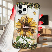 Phone case with sunflower design and 'Nana' text held by a hand in a living room.