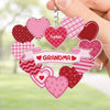 Heart-shaped keychain with 'Grandma' and 'Sofia' text, held by a hand against a blurred green background.