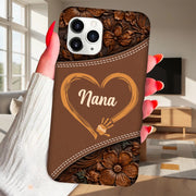 Phone case with 'Nana' design held by a hand in a living room.