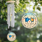 Decorative wind chime with turtle design and engraved text hanging among green leaves.