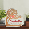 Decorative wall art with a tree design and text on a wooden base, placed on a shelf with plants and books.