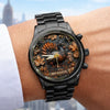 Black watch with detailed design on wrist against a blurred cityscape background